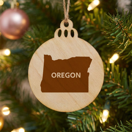 Oregon round wood Christmas ornament engraved with the state shape and OREGON in bold lettering