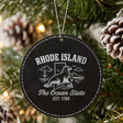 Black leatherette round Christmas ornament laser engraved with a Rhode Island design of a harbor seal and an anchor, hanging on a tree