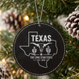 Black leatherette round Christmas ornament laser engraved with a Texas design of a longhorn skull, cactus and a lone star, hanging on a tree