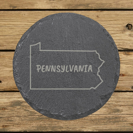 Pennsylvania round slate coaster engraved with the state outline and PENNSYLVANIA in hand-drawn brush lettering