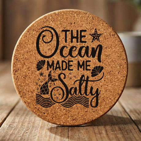 Round cork coaster laser engraved with "The Ocean Made Me Salty"