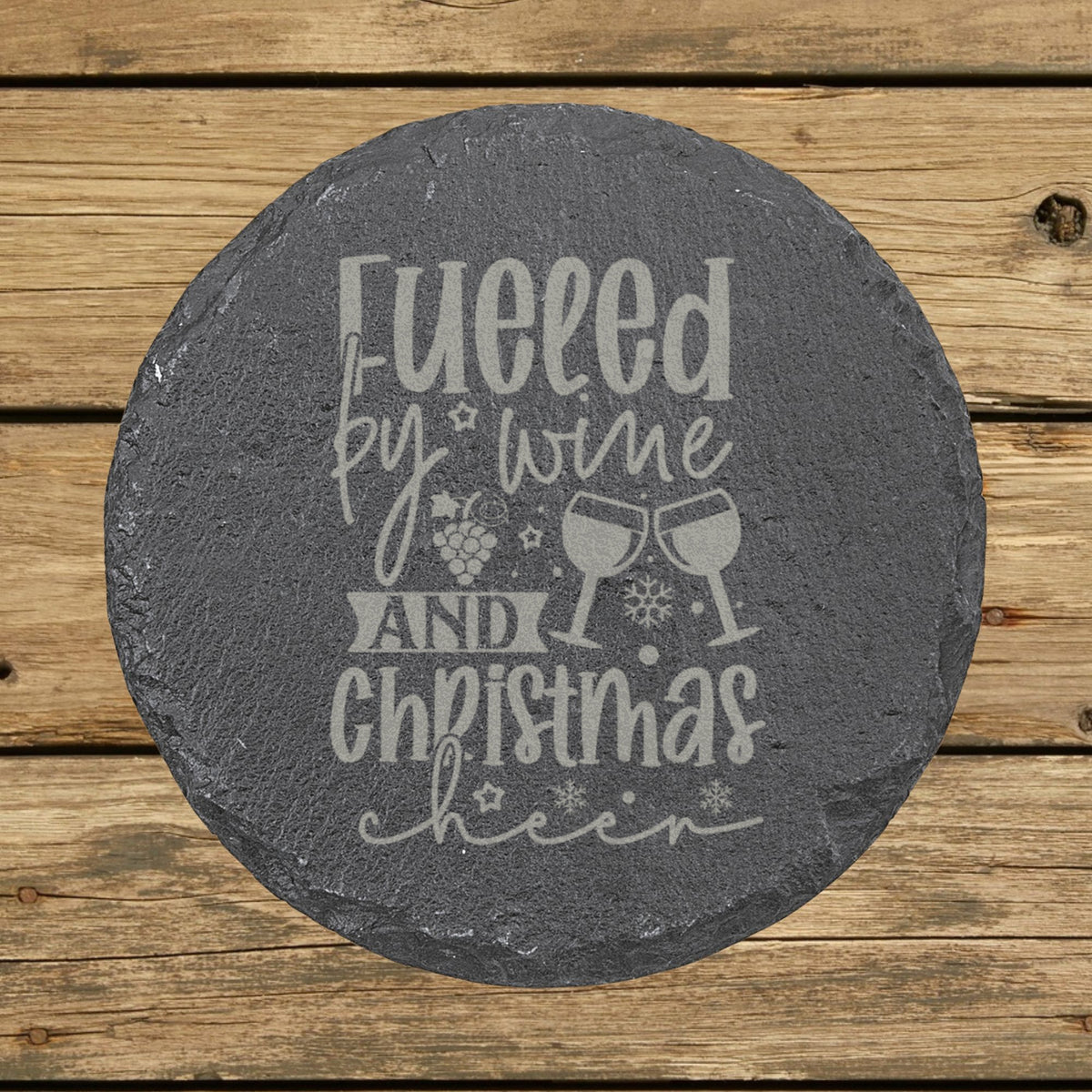 Round slate coaster laser engraved with "Fueled by Wine and Christmas Cheer"
