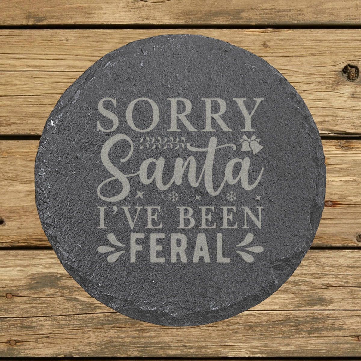 Round slate coaster laser engraved with "Sorry Santa, I've Been Feral"
