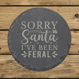 Round slate coaster laser engraved with "Sorry Santa, I've Been Feral"