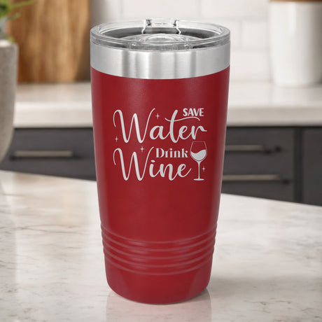 Maroon 20 oz tumbler laser engraved with "Save Water, Drink Wine", on a kitchen counter