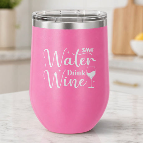 Pink 12 oz stemless wine tumbler laser engraved with "Save Water, Drink Wine", on a kitchen counter