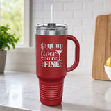 Maroon 40 oz tumbler with handle and straw laser engraved with "Shut Up Liver, You're Fine", on a kitchen counter