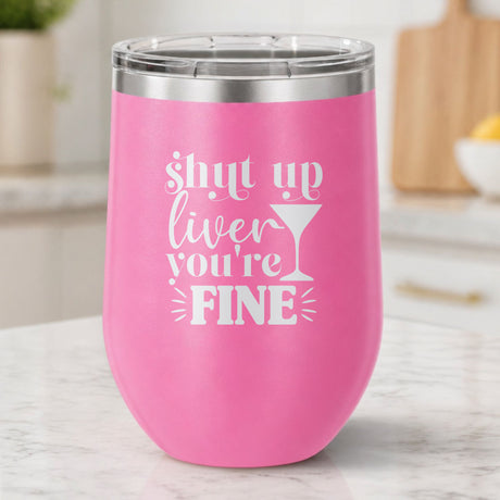 Pink 12 oz stemless wine tumbler laser engraved with "Shut Up Liver, You're Fine", on a kitchen counter