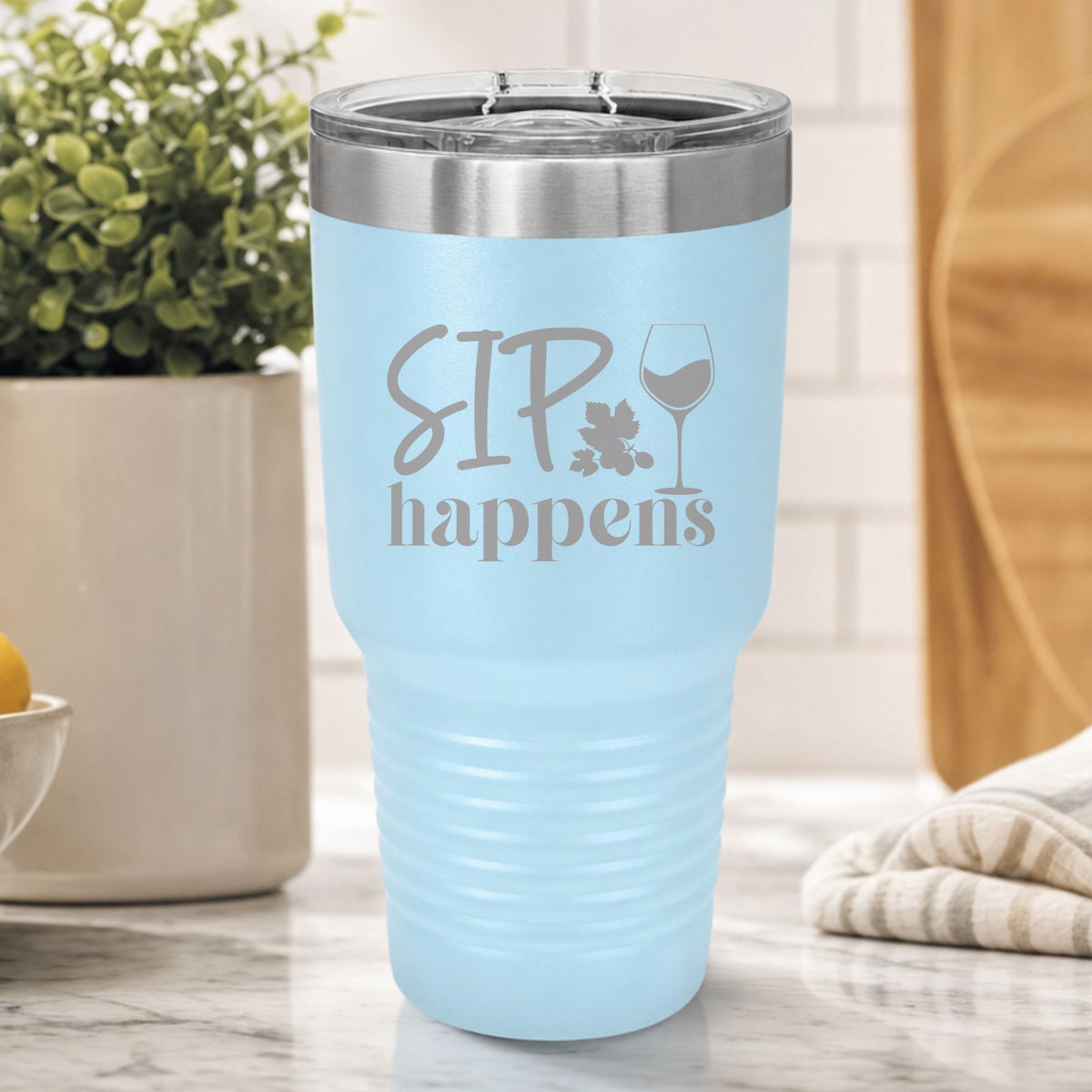 Light Blue 30 oz tumbler laser engraved with "Sip Happens", on a kitchen counter