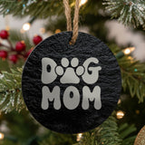 Round black slate Christmas ornament laser engraved in white with a retro bubble letter Dog Mom design with a paw print