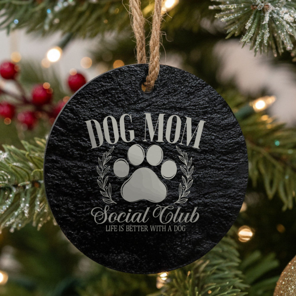 Round black slate Christmas ornament laser engraved in white with a Dog Mom Social Club crest design with a paw print and laurel wreath