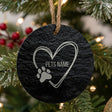 Round slate Christmas ornament engraved with a sketched heart and a paw print, showing where your pet's name goes