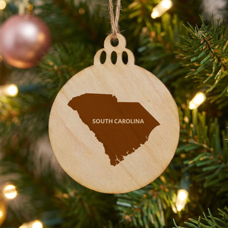 South Carolina round wood Christmas ornament engraved with the state shape and SOUTH CAROLINA in bold lettering