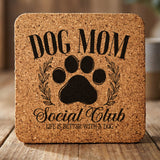 Square cork coaster laser engraved with a Dog Mom Social Club crest design with a paw print and laurel wreath