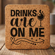 Square cork coaster laser engraved with "Drinks Are On Me", wine glass design
