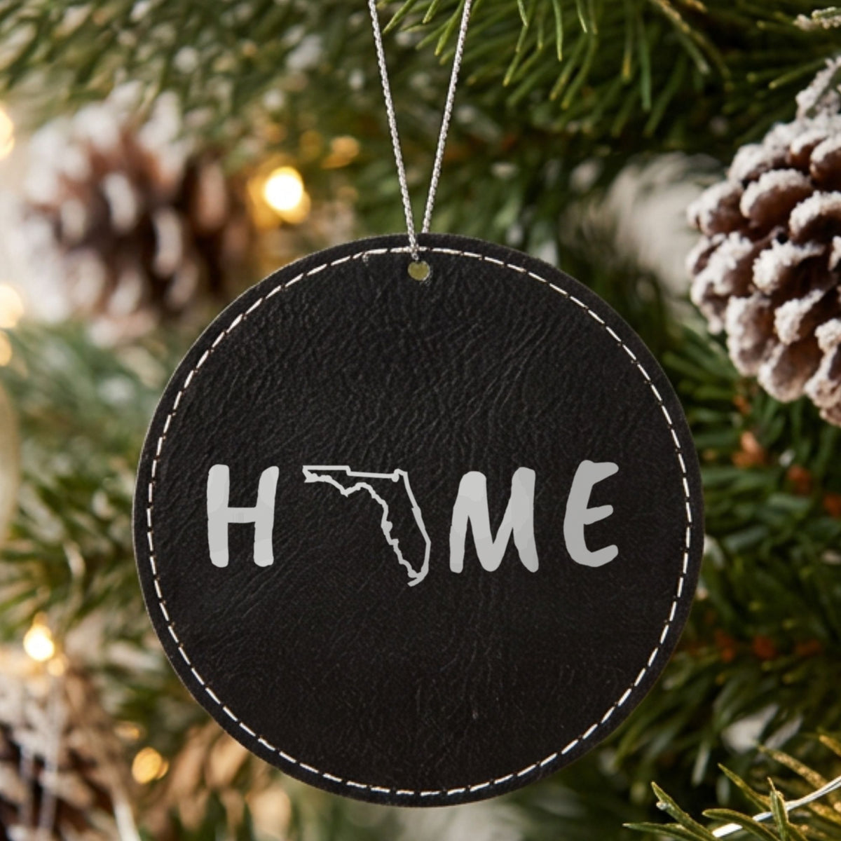 Black leatherette round Christmas ornament laser engraved with the Florida HOME Outline design, hanging on a tree