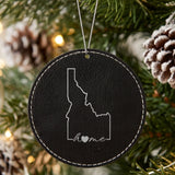 Black leatherette round Christmas ornament laser engraved with the Idaho Home Script & Heart design, hanging on a tree