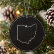 Black leatherette round Christmas ornament laser engraved with the Ohio Classic Outline design, hanging on a tree