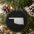 Black leatherette round Christmas ornament laser engraved with the Oklahoma Engraved State design, hanging on a tree