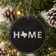 Black leatherette round Christmas ornament laser engraved with the Texas HOME Outline design, hanging on a tree