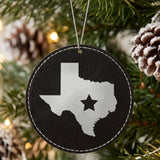 Black leatherette round Christmas ornament laser engraved with the Texas Star Accent design, hanging on a tree