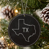 Black leatherette round Christmas ornament laser engraved with the Texas TX Initials design, hanging on a tree