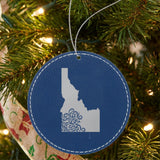 Blue leatherette round Christmas ornament laser engraved with the Idaho Floral Damask design, hanging on a tree