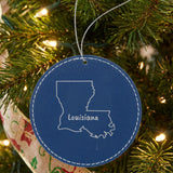 Blue leatherette round Christmas ornament laser engraved with the Louisiana Brush Lettering design, hanging on a tree