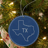 Blue leatherette round Christmas ornament laser engraved with the Texas TX Initials design, hanging on a tree