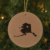 Brown leatherette round Christmas ornament laser engraved with the Alaska Heart Accent design, hanging on a tree