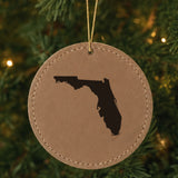 Brown leatherette round Christmas ornament laser engraved with the Florida Engraved State design, hanging on a tree