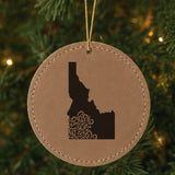 Brown leatherette round Christmas ornament laser engraved with the Idaho Floral Damask design, hanging on a tree