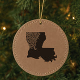 Brown leatherette round Christmas ornament laser engraved with the Louisiana Floral Damask design, hanging on a tree