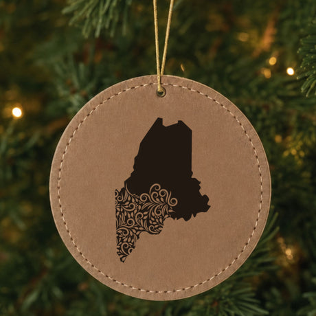 Brown leatherette round Christmas ornament laser engraved with the Maine Floral Damask design, hanging on a tree