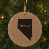 Brown leatherette round Christmas ornament laser engraved with the Nevada Bold State Name design, hanging on a tree