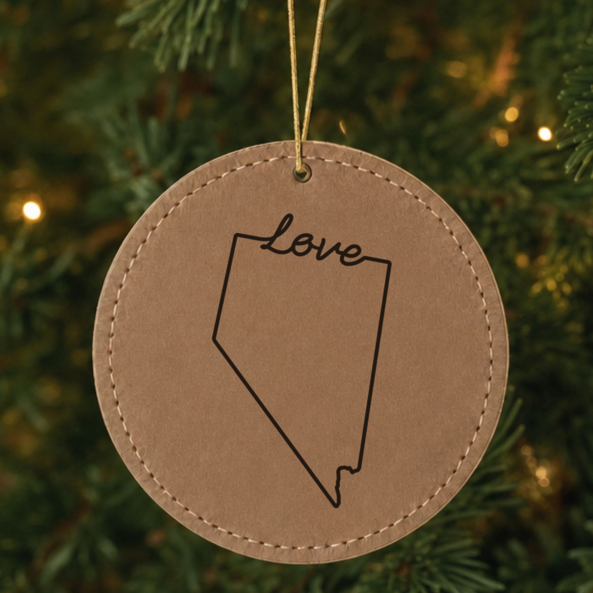 Brown leatherette round Christmas ornament laser engraved with the Nevada Hand-Drawn Love design, hanging on a tree