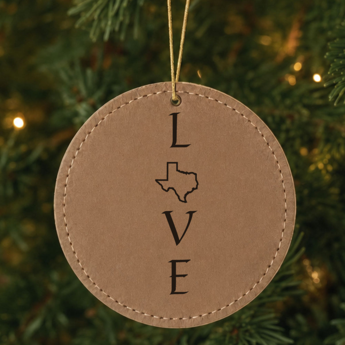 Brown leatherette round Christmas ornament laser engraved with the Texas LOVE Stacked design, hanging on a tree