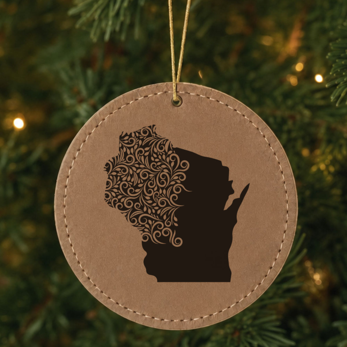 Brown leatherette round Christmas ornament laser engraved with the Wisconsin Floral Damask design, hanging on a tree