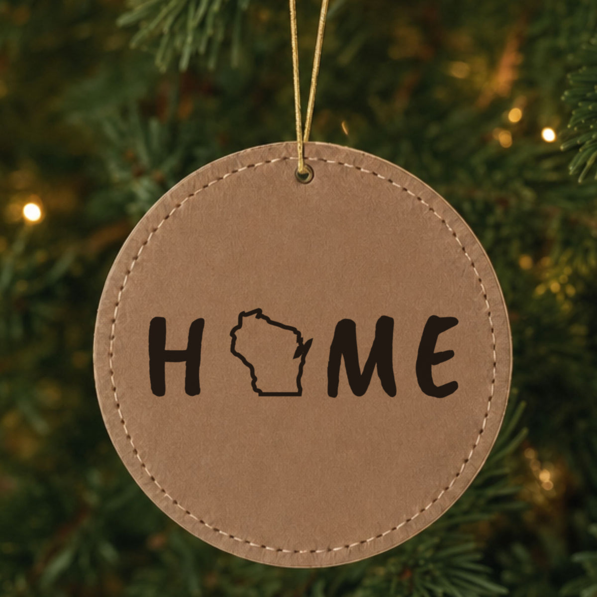 Brown leatherette round Christmas ornament laser engraved with the Wisconsin HOME Outline design, hanging on a tree