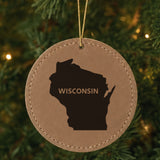 Brown leatherette round Christmas ornament laser engraved with the Wisconsin Bold State Name design, hanging on a tree
