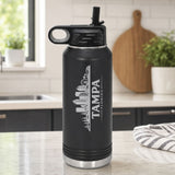 Black 32 oz insulated water bottle laser engraved with the Tampa, Florida skyline running up the side, standing on a kitchen counter