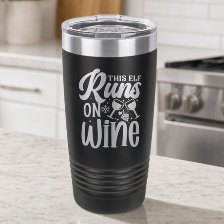 Black 20 oz tumbler laser engraved with "This Elf Runs on Wine", on a kitchen counter