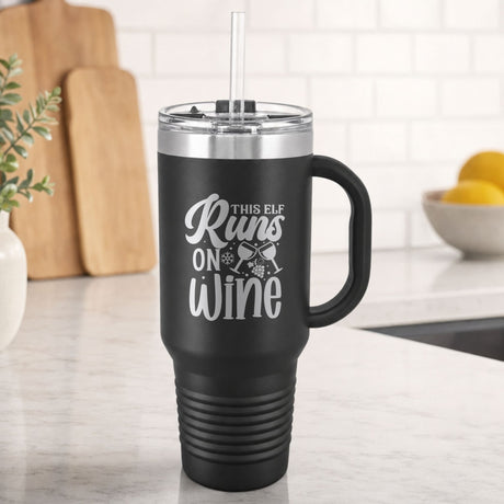 Black 40 oz tumbler with handle and straw laser engraved with "This Elf Runs on Wine", on a kitchen counter