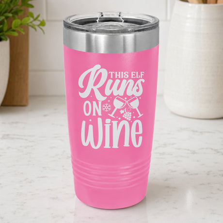 Pink 20 oz tumbler laser engraved with "This Elf Runs on Wine", on a kitchen counter