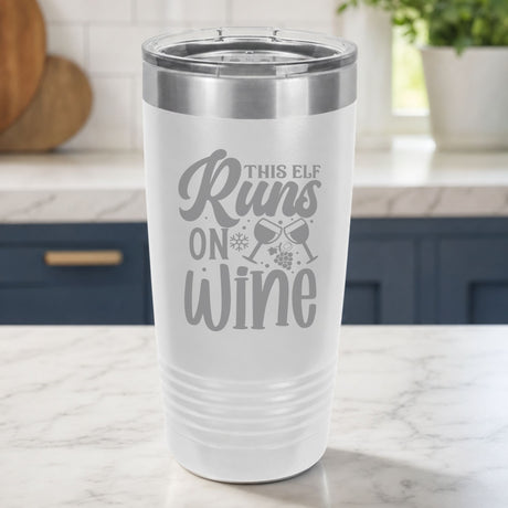 White 20 oz tumbler laser engraved with "This Elf Runs on Wine", on a kitchen counter