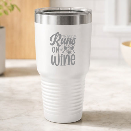 White 30 oz tumbler laser engraved with "This Elf Runs on Wine", on a kitchen counter