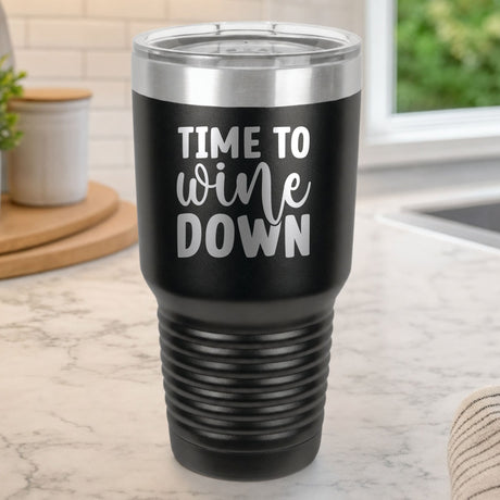 Black 30 oz tumbler laser engraved with "Time to Wine Down", on a kitchen counter