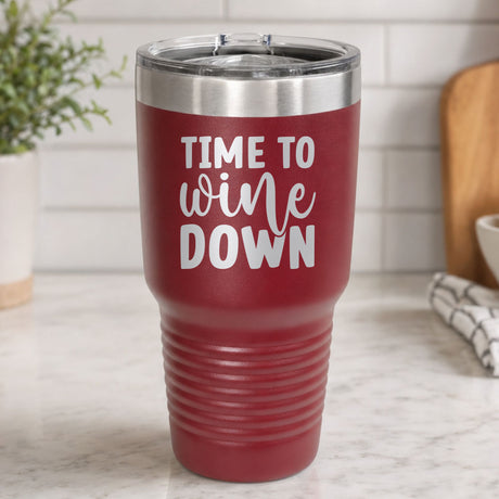 Maroon 30 oz tumbler laser engraved with "Time to Wine Down", on a kitchen counter