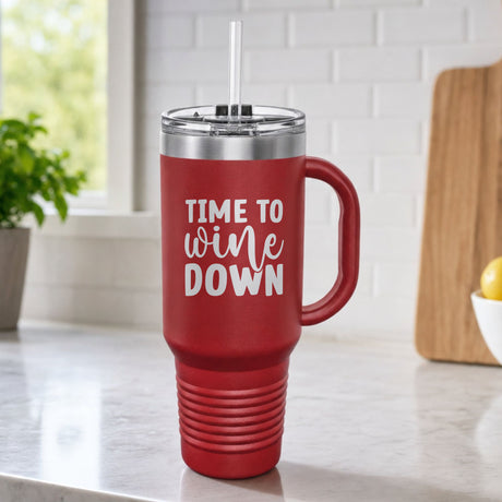 Maroon 40 oz tumbler with handle and straw laser engraved with "Time to Wine Down", on a kitchen counter