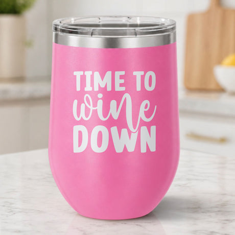 Pink 12 oz stemless wine tumbler laser engraved with "Time to Wine Down", on a kitchen counter